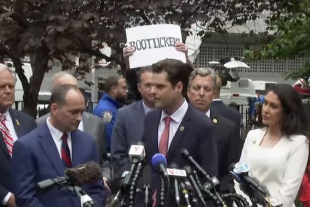 Someone holding a bootlickers sign above Matt Gaetz’s head.