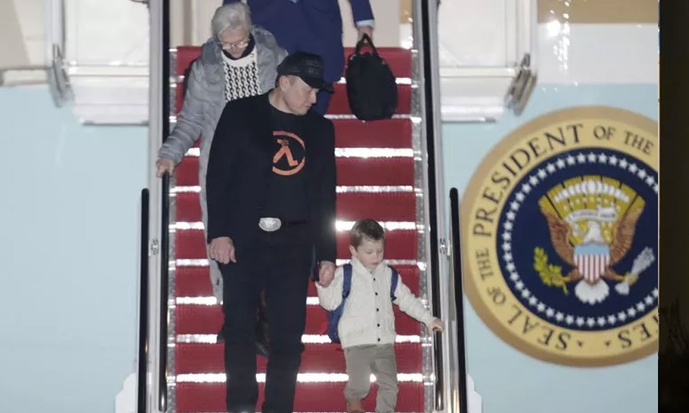 Elon Musk, front left, holds hands with his son, X Æ A-12, as he walks with his mother, Maye Musk, top left, down the stairs of Air Force One