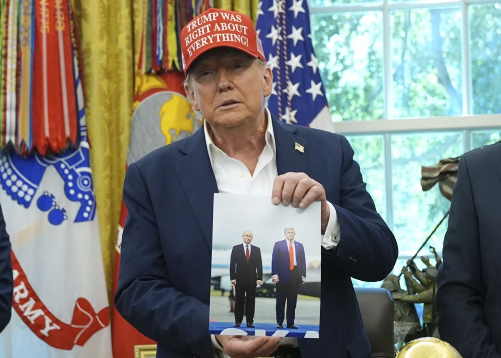 President Donald Trump shows off a photo of himself with Russian President Vladimir Putin during a recent announcement in the Oval Office of the White House.