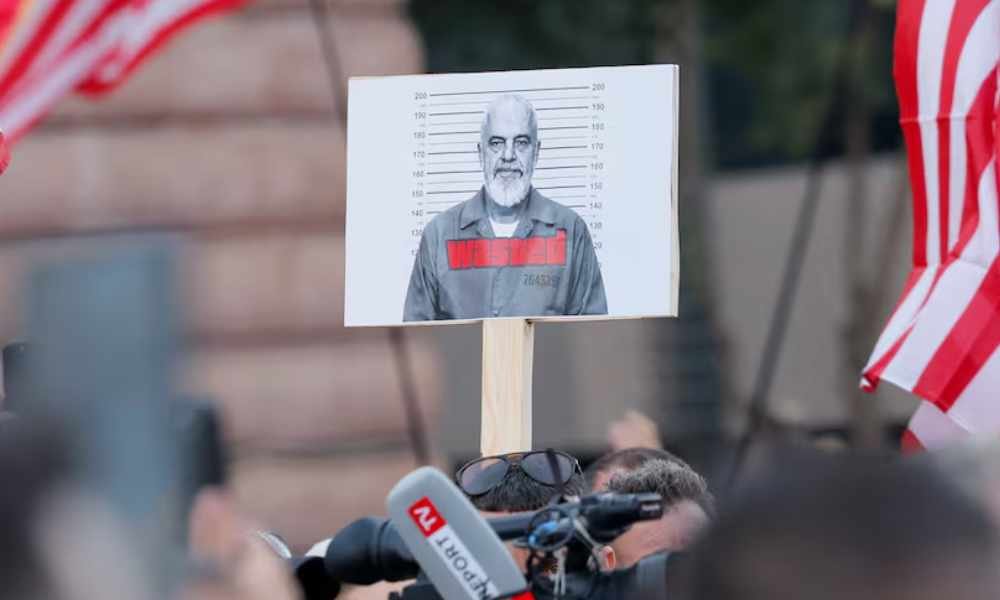 A demonstrator holds a picture of Albanian Prime Minister Edi Rama while protesters wave Albanian and American flags during a rally against a controversial luxury resort project tied to Ivanka Trump on Albania’s Adriatic coast, in Tirana on June 12, 2026. 